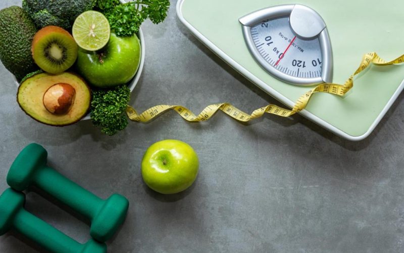 Diet and Healthy life loss weight slim Concept. Organic Green apple and Weight scale measure tap with nutrition vegan vegetable and sport equipment gym for body women diet fit.  Top view copy space.